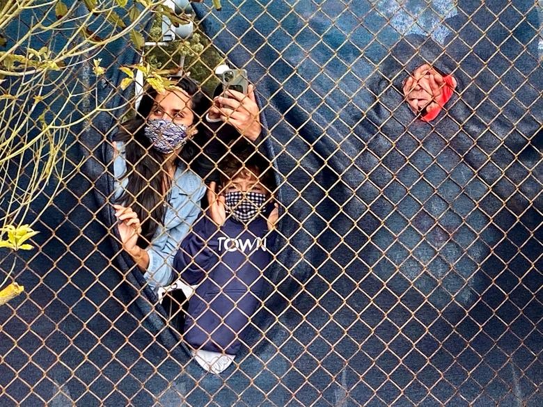 Golf fans peer through a chain-link fence to catch a glimpse of the action at the PGA Championship at TPC Harding Park in San Francisco, California, where spectators are not permitted due to the COVID-19 pandemic.   REUTERS/Rory Carroll